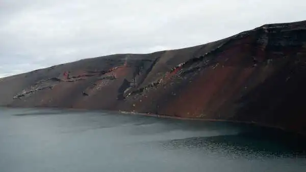 Red mountains on the side of a blue lake